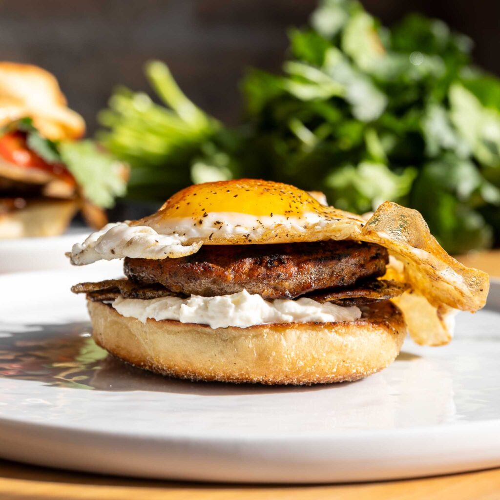 breakfast sandwich on plate bun with sausage and egg