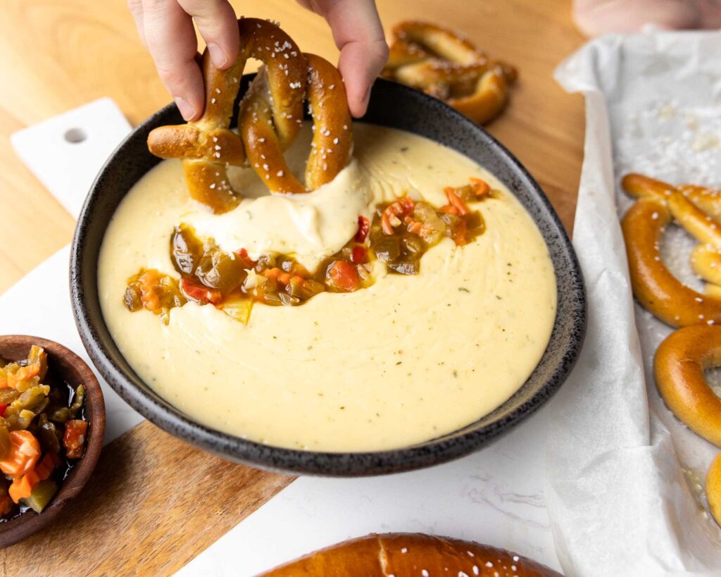 hand dipping pretzel in dip