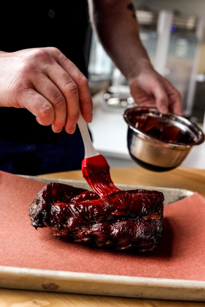 putting sauce on ribs